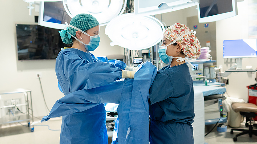 Image of Surgical Physician Assistant at Nuvance Health Danielle Mazzeo helping Marist University Physician Assistant Student Valerie DeLeon prep for work with the surgical team at Vassar Brothers Medical Center in Poughkeepsie, N.Y.