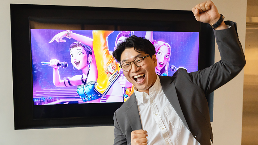 Dr. Sang-Keun Yoo, who teaches K-Pop, Film, and Dramas this fall, poses for a portrait in front of a TV showing the Kpop Demon Hunters movie. Photo by Nelson Echeverria/Marist University.