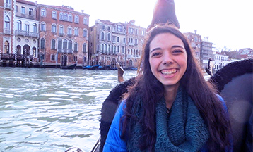 A portrait photo of Maggie Lyman sitting on a boat in a river.