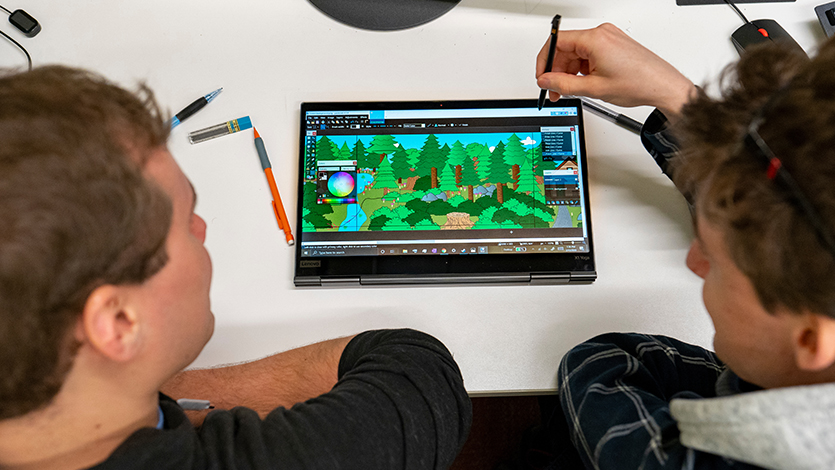 Image of two students working on a tablet that depicts a game design.