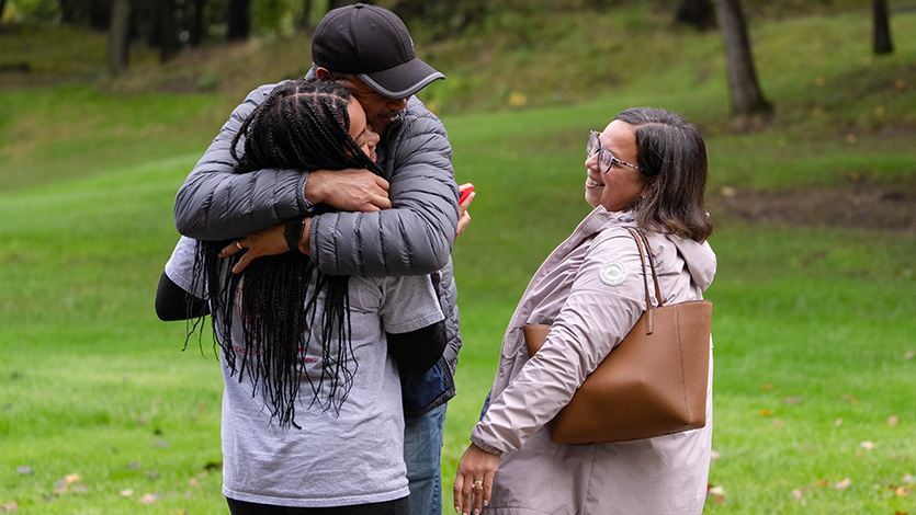 Image of student hugging parents.