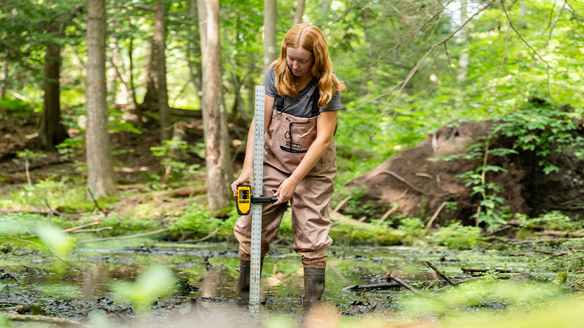 Image of Kristen Fitzgibbon '26 measuring water levels of a vernal pool.