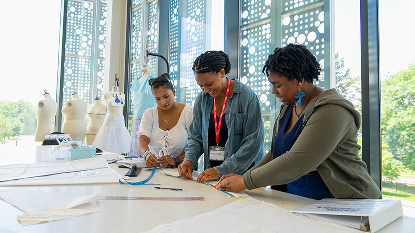 Image of costume interns Kresha Koirala ’25 (left) and Jayda Hakeem-Ali ’25 (right) work on the play reading of 'The TeeTee & Lala Show' under the supervision of Costume Mentor Celeste Jennings (center) at Steel Plant.