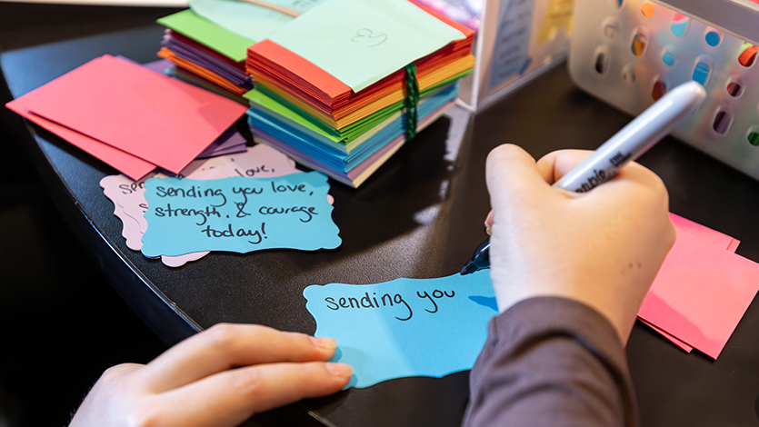 Image of A student volunteer writes&nbsp;handwritten notes for community care kits. Photo by Emily&nbsp;Portnov '29/Marist University.