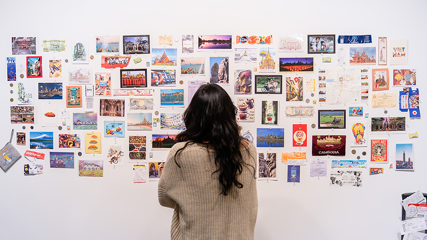 Image of A student examines a display of postcards and souvenirs collected throughout Megan’s travels.