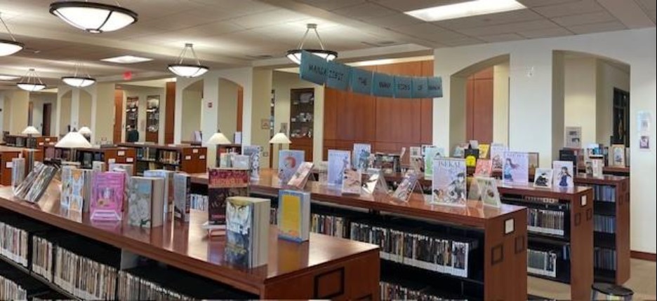 A library display featuring numerous manga books underneath a big banner reading "Mangazibit: The Many Sides of Manga" Display.